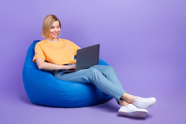 年轻女商人躺在书包里舒服地享受上网本的全长体像照片 创建基于紫色背景的代码程序 — 图库照片