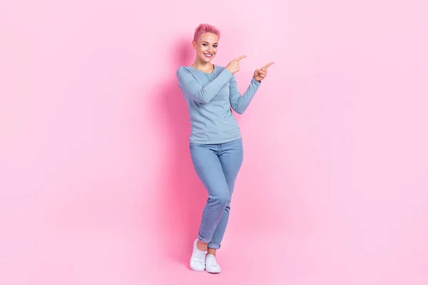 かなり光沢のある女性の完全な長さの写真は 2本の指の空のスペースを指す青いシャツを着ます ピンク色の背景 — ストック写真