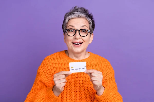 穿着橙色毛衣的女人的照片 信用卡上升 孤立的紫罗兰色背景 — 图库照片