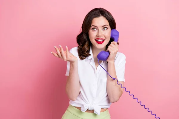 Photo of funky dreamy young lady wear white shirt speaking retro telephone looking empty space isolated pink color background.