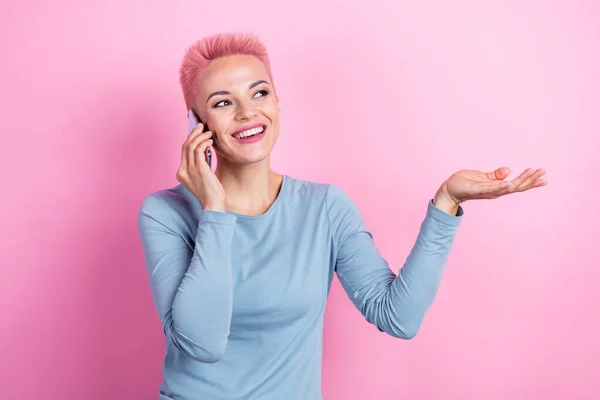 开朗的女孩穿着时髦的衣服 会说话的电话 笑着看空旷的空间 用粉色背景隔开的现代装置 — 图库照片