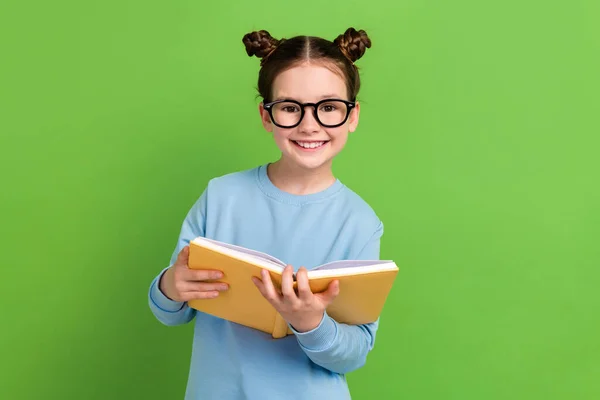 茶色の髪をビームガールの肖像画は 青いスウェットシャツをメガネのホールドブックは 緑色の背景で隔離された宿題を行う — ストック写真
