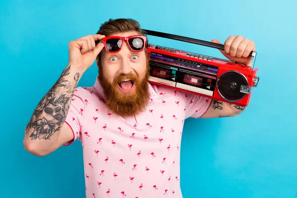 Photo of overjoyed cheerful man music lover wear trendy clothes hold radio listen audio summer vacation isolated on blue color background.