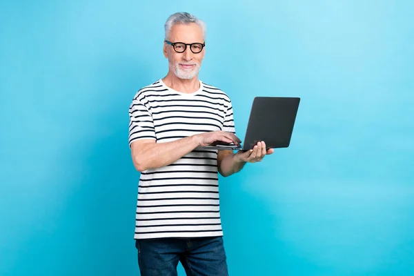 Photo portrait of nice elderly man hold netbook recruiter boss specs wear trendy striped outfit isolated on blue color background.