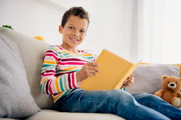 学龄前可爱的小男孩拿着橙黄色的日记本在房间里作家庭作业的照片躺在他房间里外的背景里 — 图库照片