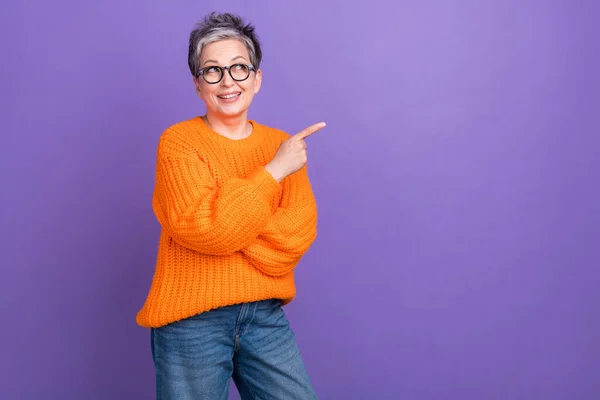 オレンジのプルオーバーを着用する高齢女性の写真は 紫色の背景に分離されたモックアップ割引を見ます — ストック写真