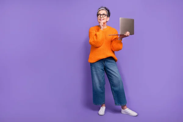 Full body length photo of clever work business woman touch chin thoughtful look empty space with laptop isolated on violet color background.