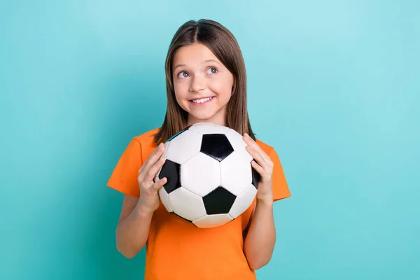 明るく満足する少女の写真 オレンジスタイリッシュなTシャツの腕ホールドボールは ティールカラーの背景に隔離された空のスペースを見ます — ストック写真
