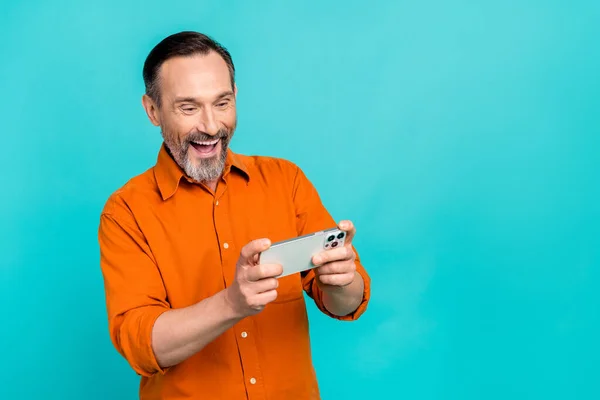 ファンキーな年金受給者の男の肖像画 遊びのビデオゲーム スマートフォンは青い色の背景で隔離された彼の昼食の自由な時間を楽しみます — ストック写真