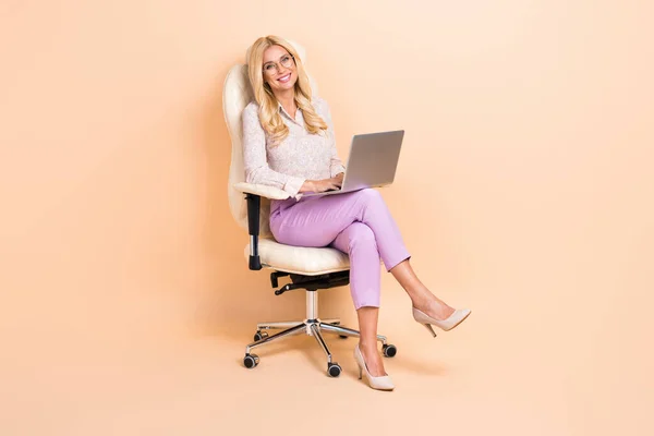 照片中快乐成功的女管理员专家坐椅使用网簿隔离米色背景 — 图库照片