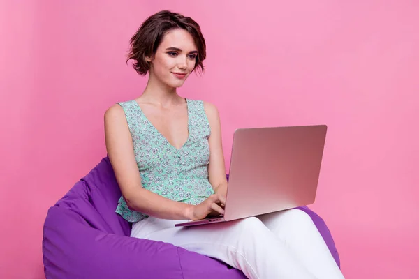 Photo of young lady programmer coding use non logo netbook advertisement confident person sitting beanbag isolated on pink color background.