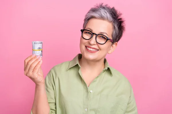图为满意的退休人士 商界女性祖母身穿卡其布的时髦衬衫 手持粉色背景的美元钞票 — 图库照片