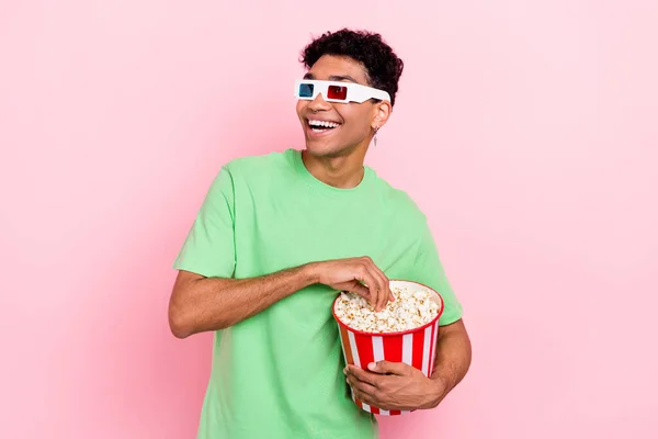 ポジティブな幸せな男性の写真 トレンディな緑の服を着る ポップコーンを食べる ピンク色の背景に隔離された空のスペース面白いフィルムを見上げる — ストック写真