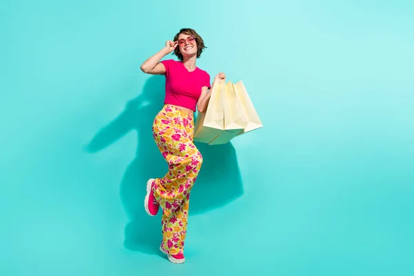 ファンキーな甘い女性の花のプリントパンツの完全な長さの写真 買い物客の空のスペースを隔離されたターコイズ色の背景 — ストック写真