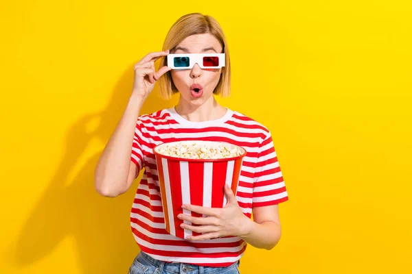 スピーチレスの女性の写真ストライプTシャツタッチ3Dメガネホールドポップコーンウォッチ興奮する映画は活気に満ちた黄色の背景で隔離されています — ストック写真