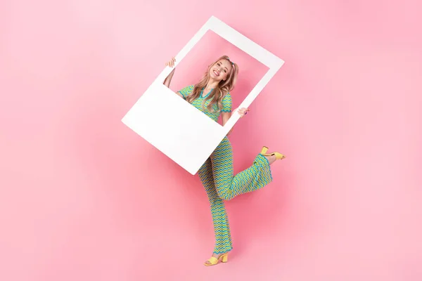 全长照片 年轻貌美的女性手持照片干部装扮时髦的绿色印花衣服 与粉色背景隔离 — 图库照片