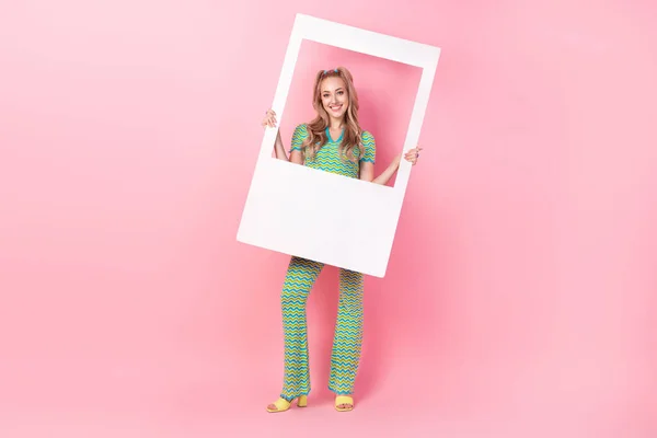 かなり若い少女のフルボディ写真は ピンク色の背景に隔離されたトレンディな緑の印刷物の服をインスタント写真フレームを保持します — ストック写真