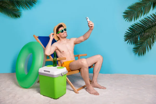 ハンサムなクールな男の完全な長さの写真日光浴ラウンジチェアレコーディングビデオBigog隔離された青い色の背景 — ストック写真