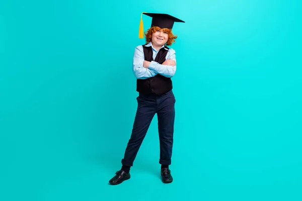 stock image Full size portrait of positive successful schoolkid folded hands posing wear mortarboard hat isolated on turquoise color background.