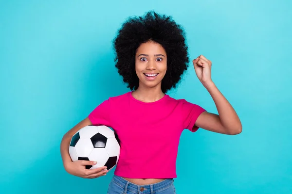 青い色の背景で隔離されたスタイリッシュなTシャツハンドホールサッカーボールウィンマッチのエクスタシーなオーバーイジーな女子高生の肖像画 — ストック写真