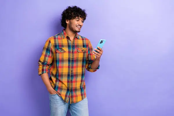 英俊潇洒的人拿着的照片用智能手机空出的空格广告隔离在紫色的背景下 — 图库照片
