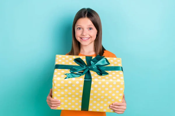 ポジティブかわいい親切な女の子の写真は オレンジ色の背景に隔離された大きな箱パッケージ誕生日プレゼントを保持しています — ストック写真