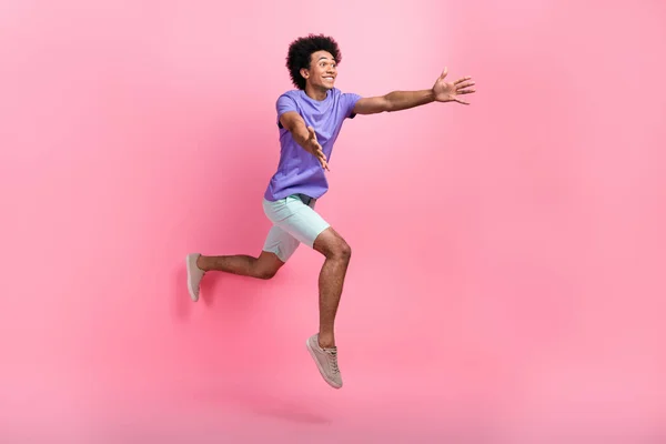Full size photo of overjoyed ecstatic guy wear blue t-shirt pants run look empty space catch object isolated on pink color background.