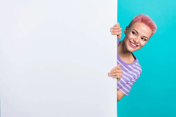 照片上 快乐的年轻女士身穿紫色条纹T恤 藏在纸上 白色横幅空旷的空间新闻在青色背景下被隔离 — 图库照片