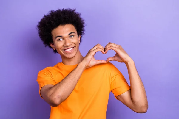 服装肖像乐观的年轻人穿着橙色的流行T恤 展示他的爱情象征手指被紫色背景隔开 — 图库照片