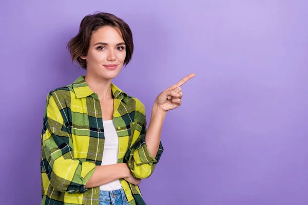 若い女性の写真は ヴァイオレット色の背景に隔離された指の空スペース広告プロモーションショップを指示チェッカーされたトレンディなシャツを着用します — ストック写真