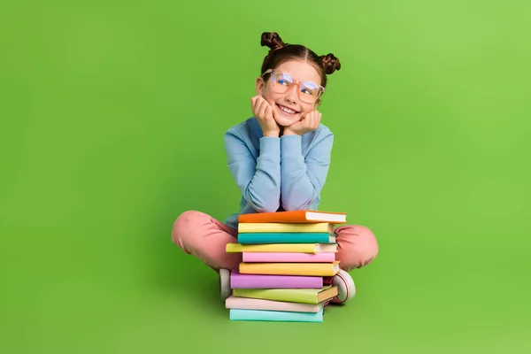 全神贯注 梦幻般 可爱的小女孩身穿蓝色套头衫 坐在书架上 看起来空荡荡的 与绿色背景隔离 — 图库照片