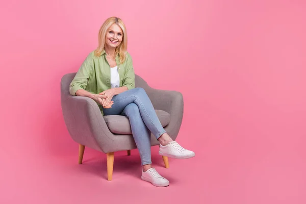美しい陽気な人の完全なボディ肖像画はピンク色の背景で隔離された居心地の良い椅子の空のスペース広告を座ります — ストック写真
