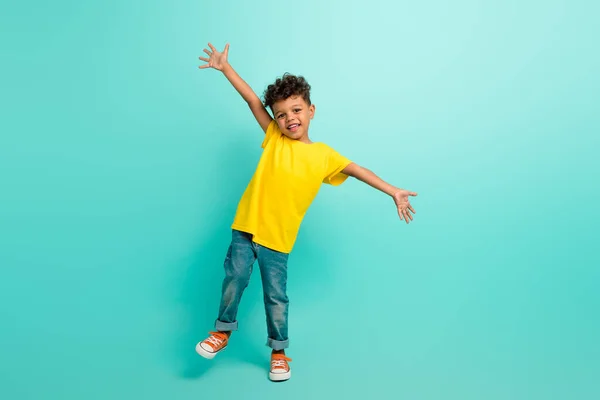 茶色の色の背景に隔離されたスタイリッシュなTシャツを着用した陽気なポジティブな小さな男の子の全長の写真 — ストック写真