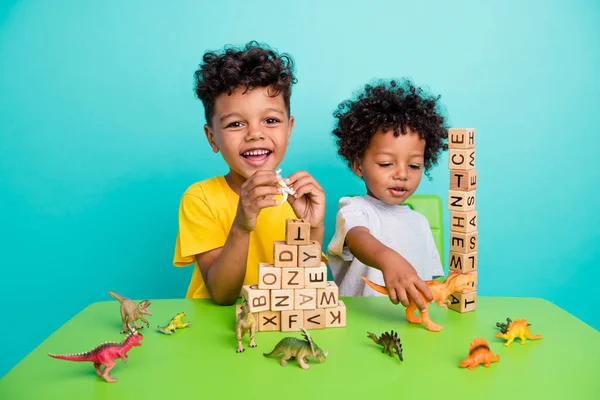 木製の立方体ピラミッドを演奏する愛らしい小さな少年たちのフルサイズの写真は シアンカラーの背景に隔離された楽しい服装をしています — ストック写真
