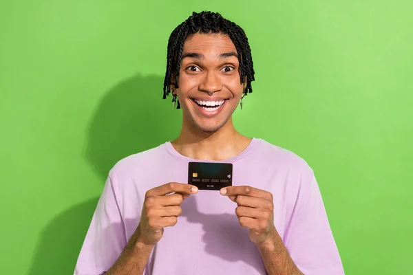 stock image Portrait of astonished eccentric person toothy smile arms hold demonstrate debit card isolated on green color background.