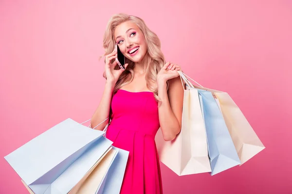 Portrait of funny pretty lovely lady hold mall bags speak chatting telephone isolated on pink color background.