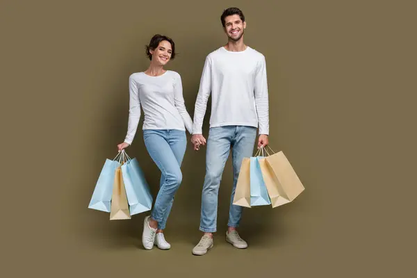 良い気分の完全な長さの写真 ポジティブな妻の夫は 隔離された茶色の背景と一緒にショッピングを歩く白いシャツを着た — ストック写真