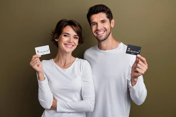 Photo of attractive positive people wear white trendy clothes hand hold plastic bank card buy online isolated on brown color background.