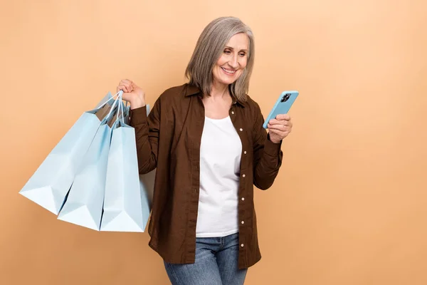 オンラインストアバーゲンを閲覧年金女性の写真 ベージュ色の背景で隔離されたショッピングの最高の提案注文オンラインパッケージ — ストック写真