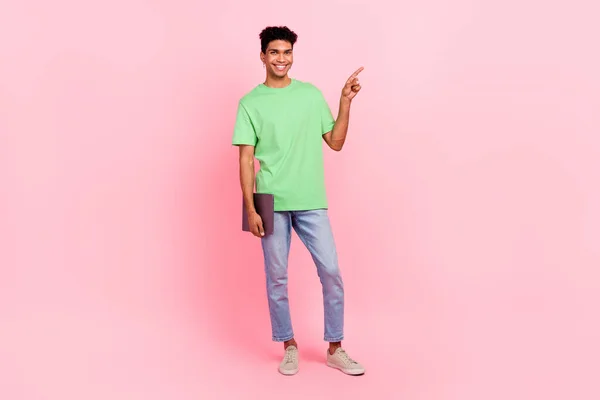 stock image Full length photo of positive man dressed stylish t-shirt hold laptop indicating at offer empty space isolated on pink color background.