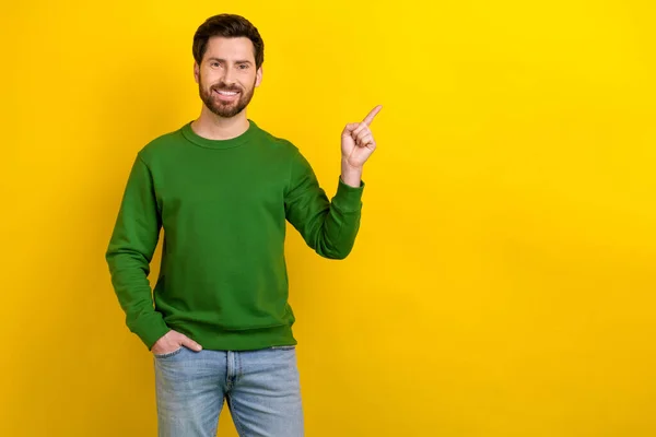 インデックス指を指示する魅力的な男の写真 空スペースバナーポスター スウェットシャツジーンズを着用 イエローカラー背景 — ストック写真