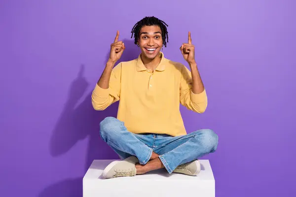 Full body photo of sitting comfort youth man surprised pointing fingers up click website sale advert isolated on violet color background.