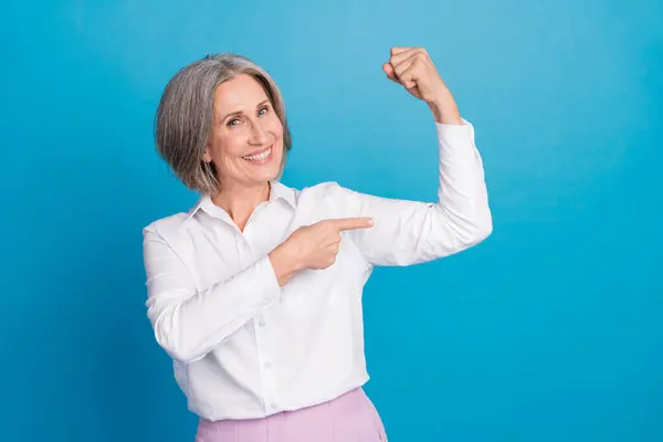 照片上 快乐而积极的女人穿着白衬衫 指尖着手指 手臂二头肌孤立的蓝色背景 — 图库照片