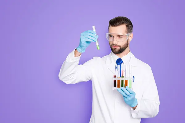 在白大褂 手套分析 看着在他的手臂上的多色液体试管 在灰色背景下孤立的密集的科学家的肖像 — 图库照片