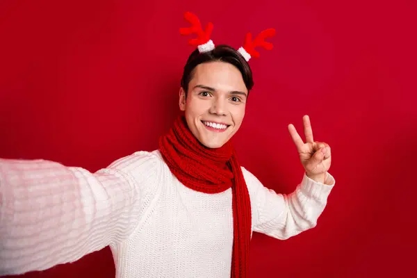 有趣的流行圣诞博客作者 穿着驯鹿鹿角 展示V字形标志 喜欢录制红色背景的孤立视频 — 图库照片