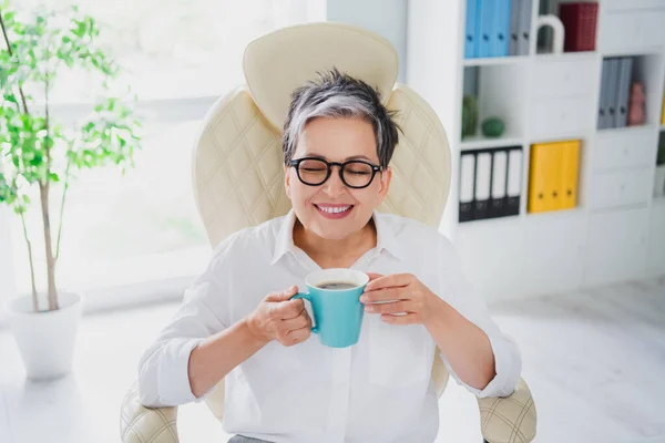 退休女性成功的女商人早晨在室内独立的背景下享受着香味浓郁的浓缩咖啡 — 图库照片