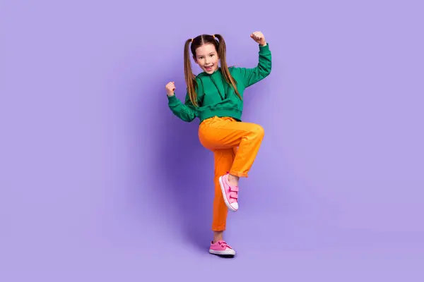 全长照片 照片上穿着绿色连帽衫的漂亮小女孩举起拳头 孤立的紫色背景 — 图库照片