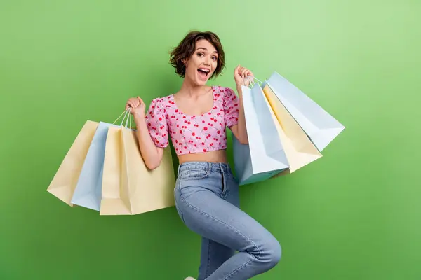 Photo of positive funky lady wear pink blouse rising shoppers smiling isolated green color background.