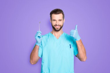 Portrait of joyful cheerful dental assistant in lab blue uniform gesturing thumbup approve advice yes done sign with finger, having tool in hand, isolated on grey background. clipart