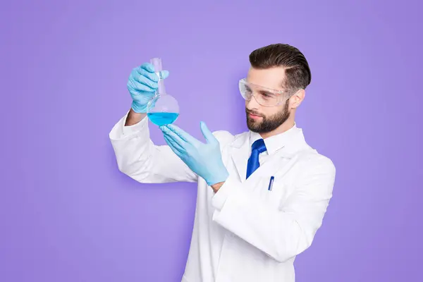 聚精会神的科学家的画像 他身穿白色的实验室外套 手套检查 他的胳膊上夹着多种颜色的液体 在灰色的背景下被隔离 — 图库照片